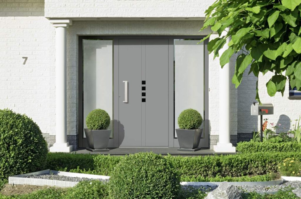 Graue Aluminium-Haustür mit schmalen Lichtausschnitten an einem weißen Klinkerhaus