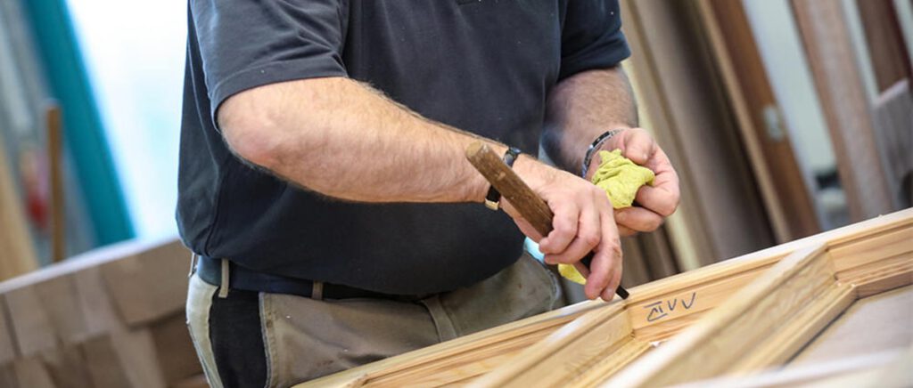 Tischler bearbeitet den Rahmen eines Holzfensters in der Werkstatt